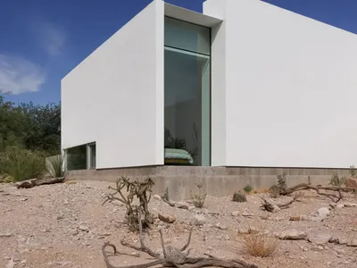 Open living area with a large white wall, two windows, and natural light