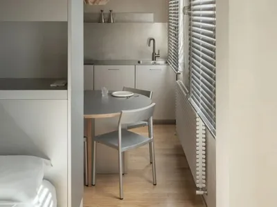 Cozy open kitchen with a dining table, chairs, and a sink, featuring a bowl and a bottle, with a focus on functionality and comfort