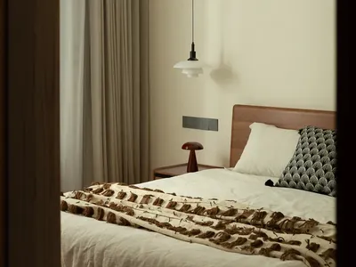 A serene bedroom with a white wall, wooden headboard, and a chair, featuring a cozy bed setup with two pillows