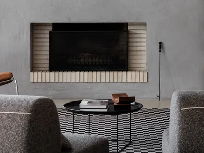 Cozy living space with a brick fireplace, two couches, a chair, and a book, creating a warm and inviting atmosphere