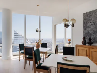 Dining room with a large window offering a city view, modern furniture, and a vase on the table