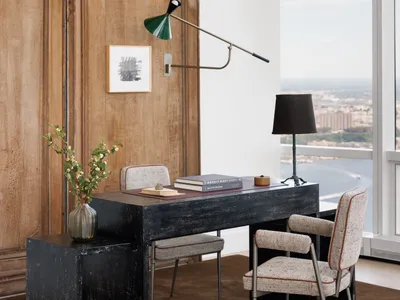 Well-lit living area with a wooden door, desk, chair, and lamp, creating a cozy atmosphere for relaxation or work