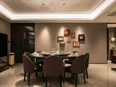 A well-lit dining area with a large wooden table, multiple chairs, and decorative vases, set for a meal with various tableware and utensils