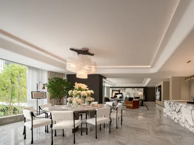 A luxurious dining room with a white table, surrounded by white chairs, and decorated with potted plants and flower vases