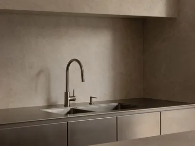 Industrial kitchen with a metal sink and marble countertop, featuring a spacious layout with a large wall