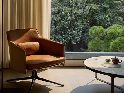 Cozy living space with a leather chair, two couches, and natural light from a large window