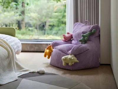 溫馨臥室內有紫色椅、木質地板與毛絨玩具，營造溫暖舒適的氛圍