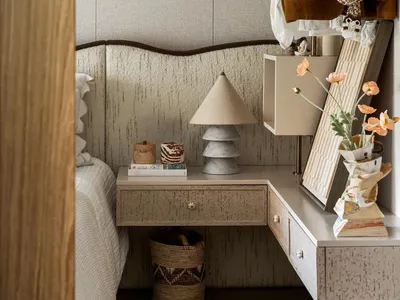 Cozy bedroom with a bed, dressers, a mirror, and books, creating a warm and inviting atmosphere