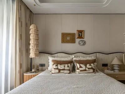 A well-lit bedroom with a large white bed, brown pillows, and a cozy atmosphere