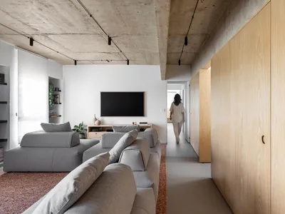 A comfortable open living area with a couch, chairs, TV, and potted plants, perfect for relaxation and socializing