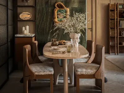 Dining area with a wooden table and chairs, surrounded by books and decorative items, creating a cozy atmosphere