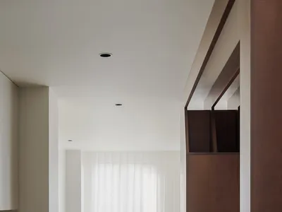 Empty white living room with a wooden floor, two chairs, and natural light from windows