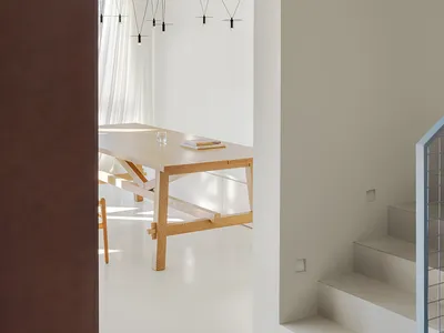 Open living space with a wooden dining table, chairs, and a modern couch, featuring clean lines and minimalistic decoration