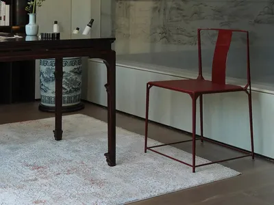 Cozy living space with a red chair, books, vases, and a table, inviting relaxation and leisure activities