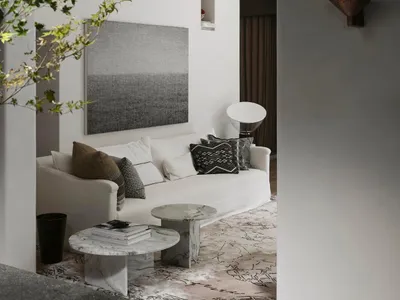 Cozy living space with a white couch, two chairs, a dining table, and a potted plant, surrounded by books and natural light