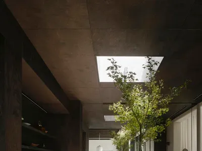 深色木質櫥櫃、花崗岩檯面與黑色家電的現代廚房，設有雙水槽、冰箱，以及帶椅子的餐桌