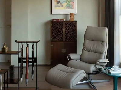 A comfortable living space with a leather chair, two smaller chairs, and a wall hanging, creating a relaxing atmosphere
