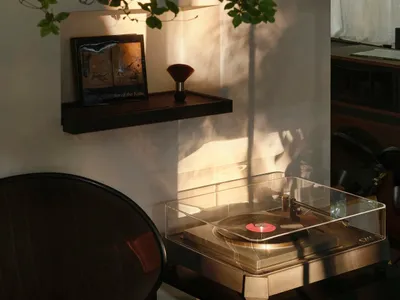 Cozy modern living space with a chair, table, and record player, surrounded by books in a home setting