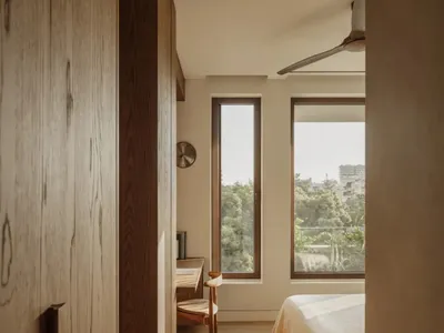 Bright and inviting bedroom with two beds, a desk area, and natural light from a large window
