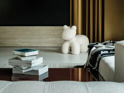 Cozy living space with a flat screen TV, couch, books, and a chair, with a warm and inviting atmosphere
