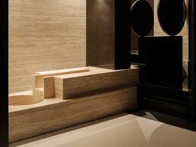 A dark and moody bathroom with a black and white color scheme, featuring a sink and toilet, and two round objects, one near the sink and another near the toilet