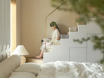 一位女子在書櫃前的樓梯上閱讀，周圍環繞溫暖舒適的氛圍，木製樓梯與書架上數本書籍