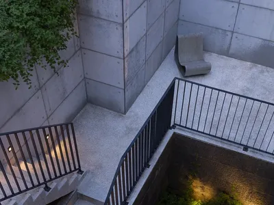 A dark and mysterious basement area with a metal staircase leading down, surrounded by shadows and a sense of depth