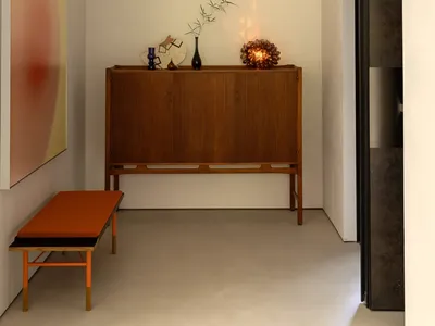 A cozy living space with a wooden cabinet, vases, and a potted plant, creating a warm and inviting atmosphere