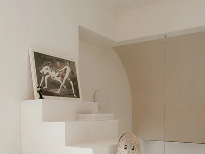 Clean and minimalist interior space with a staircase, artwork, and a vase, featuring white walls and a neutral color palette
