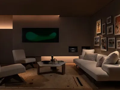 Cozy modern living space with a white couch, flat screen TV, and neutral tones, set against a backdrop of concrete walls
