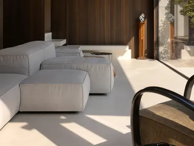 A modern living area with a couch, chairs, and bench, surrounded by wooden walls, natural light, and a dining table, creating a warm and inviting atmosphere