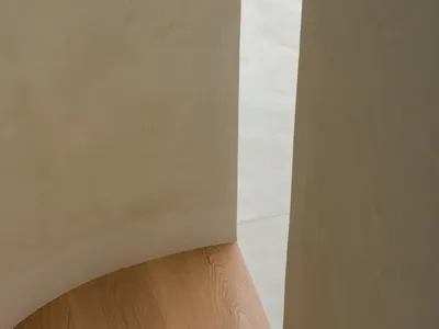 A curved staircase with a wooden handrail in a well-lit interior space with a warm atmosphere