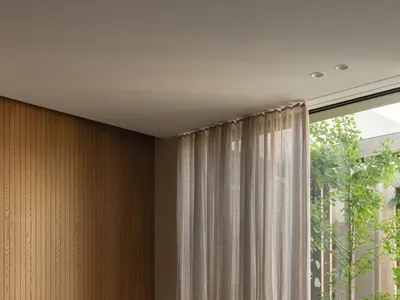 Cozy bedroom with wooden walls and floors, featuring two beds, a chair, and a large window allowing natural light to enter
