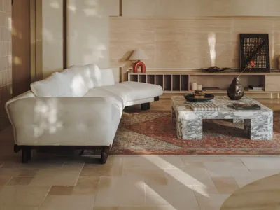 Cozy living area with a white couch, wood paneling walls, a rug, and a dining table