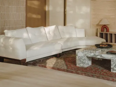 Bright and inviting living area with white couches, a coffee table, and sunlight streaming through the windows