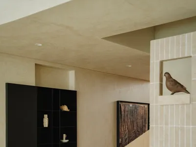 A well-lit living area in a coastal villa with a white couch, birds perched on surfaces, and decorative vases, creating a comfortable and inviting atmosphere
