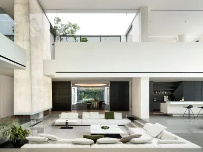 Cozy open living area with a white couch, hardwood floor, and potted plants, well-lit by natural and artificial light