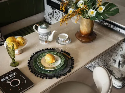 Sophisticated dining area with a white chair, table, vase of flowers, cups, and a fruit bowl