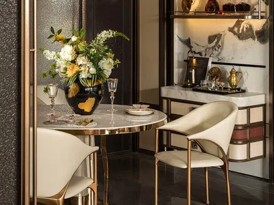 Dining area with a round table, chairs, a vase with flowers, and wine glasses, creating a luxurious and inviting atmosphere