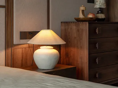 Cozy bedroom with wooden walls, a dresser, two lamps, and a vase, creating a warm and inviting atmosphere