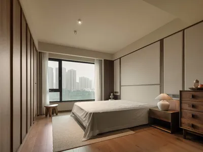 Cozy bedroom with a white bed in front of a window, wooden floor, and two chairs on either side