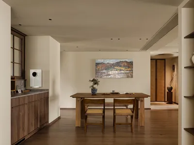Warm and inviting open concept living space with a wooden dining table, chairs, and a potted plant