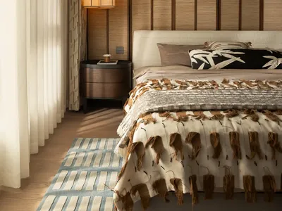 A cozy bedroom with a large bed, brown blanket, and wooden floor, creating a warm and inviting atmosphere