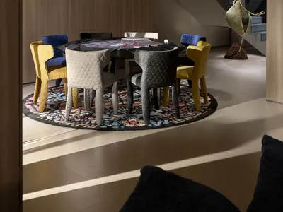 A modern dining space with a colorful array of chairs surrounding a dining table, set for a game night with cups and bowls, and a nearby couch adding to the cozy atmosphere