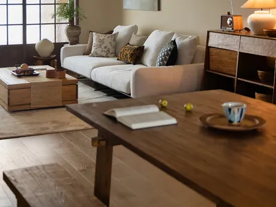 Cozy living room with a white couch, chairs, potted plants, vases, bowls, cups, books, and a remote control, creating a warm and inviting atmosphere