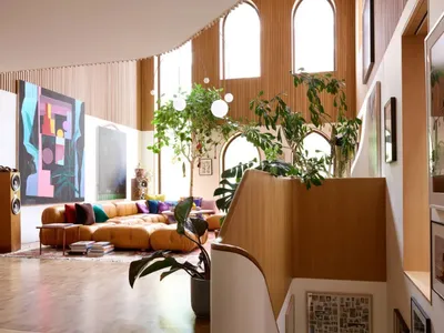 Open living area with a couch, staircase, potted plants, and a dining table, creating a cozy and inviting atmosphere