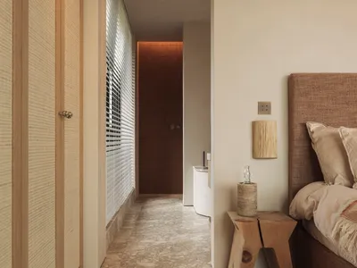 A calm and inviting bedroom with a large bed, white walls, wooden floors, and a few personal touches