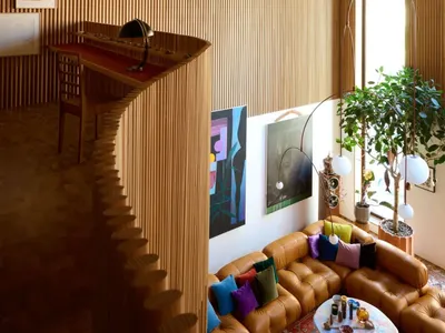 Cozy open concept living area with a large couch, two chairs, potted plants, and decorative vases, creating a warm and inviting atmosphere