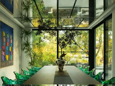 A modern dining area with a large glass table surrounded by multiple chairs, creating a sophisticated atmosphere