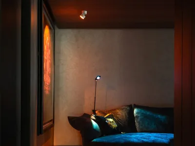 Cozy living space with a black couch, two chairs, and a small table, surrounded by artwork and suggesting a comfortable atmosphere